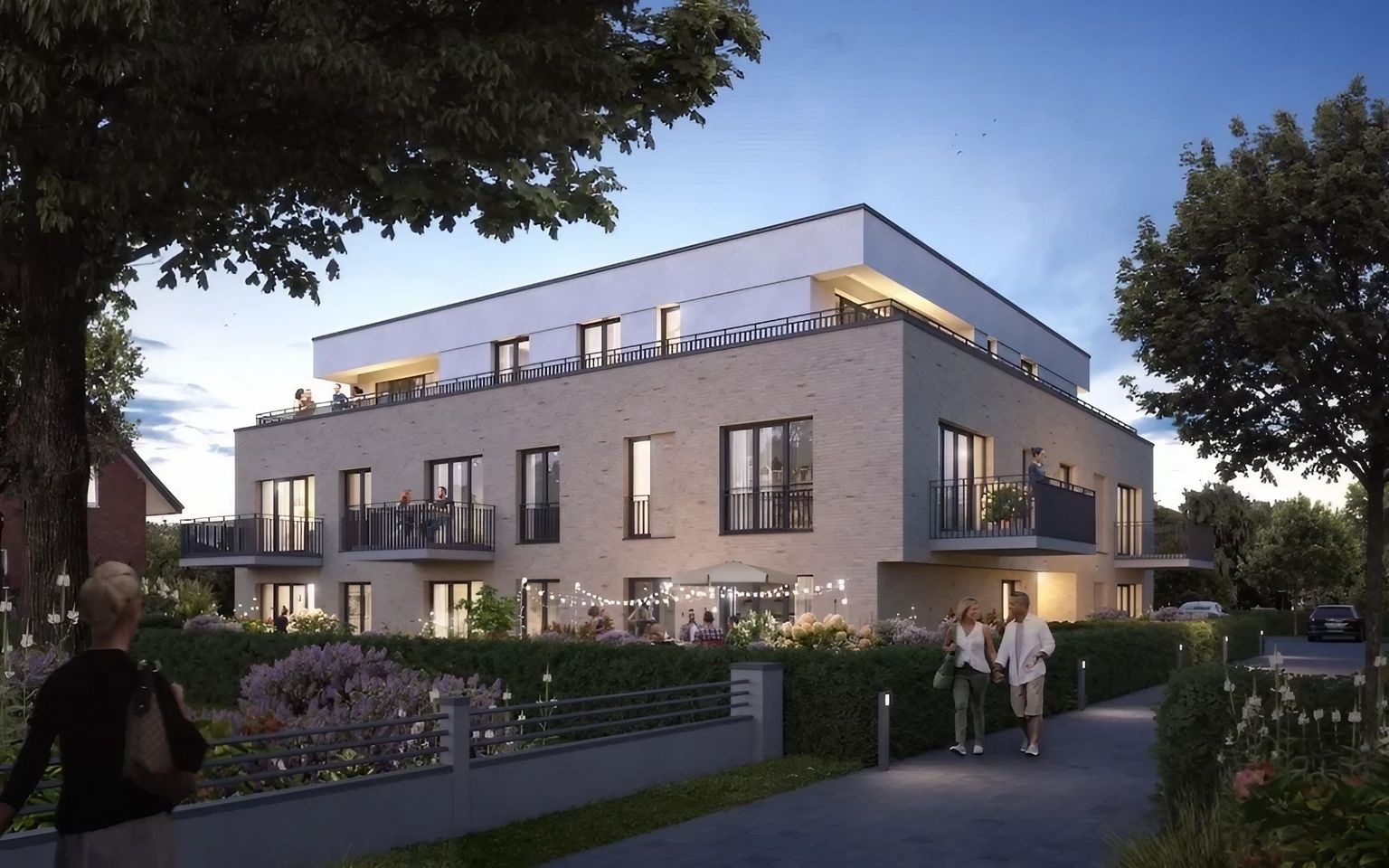 Mehrfamilienhaus in Hövelhof mit Balkonen und beleuchteter Außenanlage bei Dämmerung.