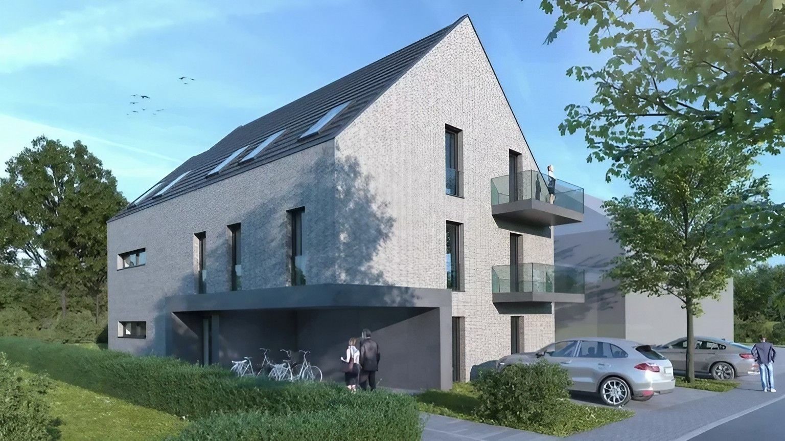 Mehrfamilienhaus in Delbrück mit grauer Klinkerfassade, Satteldach und Glasbalkonen.