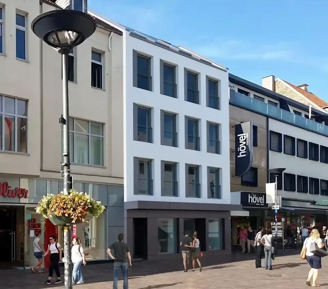 Modernisiertes Wohn- und Geschäftshaus mit weißer Fassade in der Paderborner Fußgängerzone.